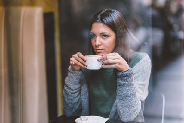 istock Young Woman Drinking Coffee While Sitting At Sidewalk Cafe 1135918463