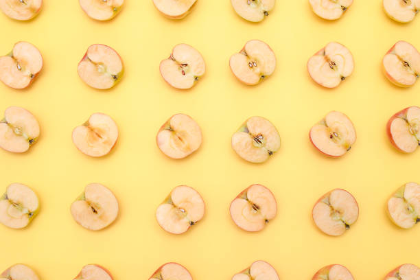 istock Background of cut in half apples on yellow background 1135920862