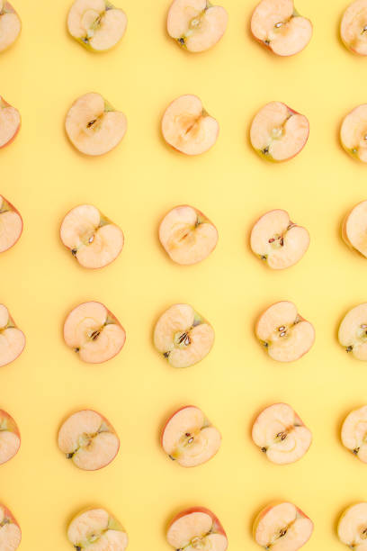istock Background of cut in half apples on yellow background 1135920966
