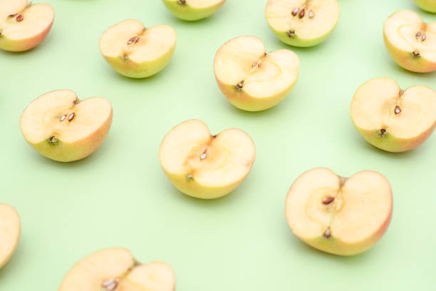 istock Background of cut in half apples on green background 1135921272