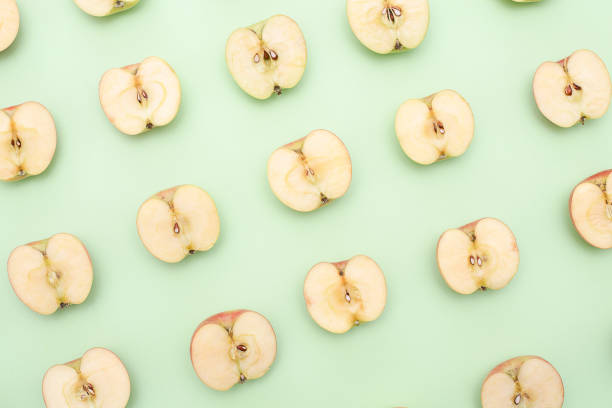 istock Background of cut in half apples on green background 1135921357