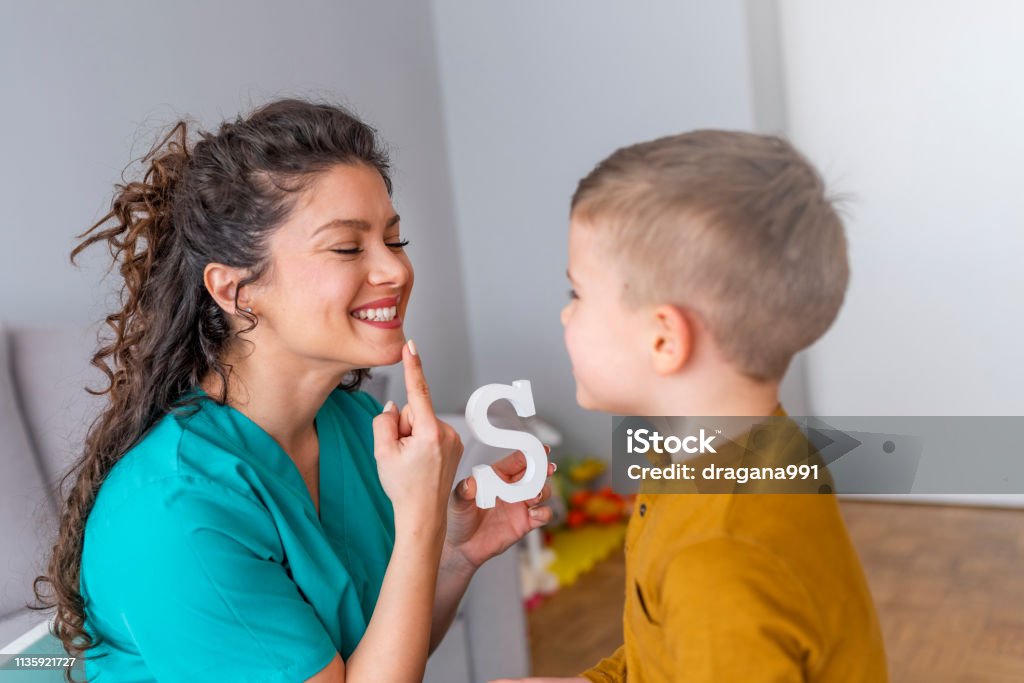 Shot de un terapeuta del habla durante una sesión con un niño pequeño - Foto de stock de Niño libre de derechos