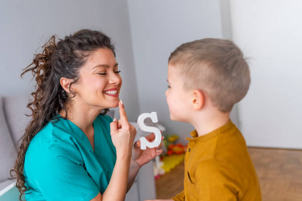 выстрел логопеда во время сеанса с маленьким мальчиком - reading and writing classroom alphabet learning стоковые фото и изображения