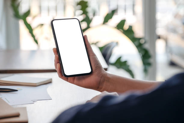 istock Mockup image of a woman holding and using mobile phone with blank screen while working in office 1135923884