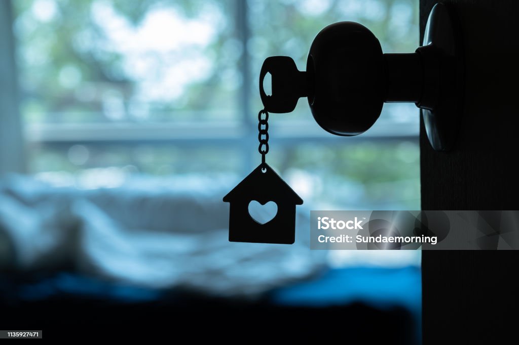 Chave da casa com o chaveiro Home no buraco da fechadura na porta de madeira, espaço da cópia - Foto de stock de Casa royalty-free