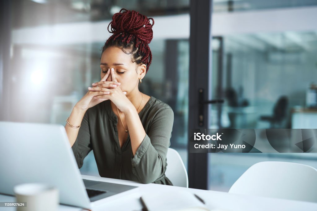 She has one too many deadlines to deal with Shot of a young businesswoman looking stressed out while working in an office Working Stock Photo