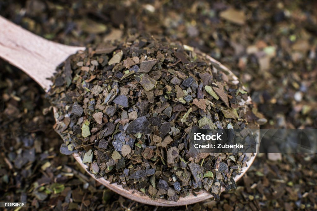 Guayusa Dry Tea Leaves in Spoon Ayahuasca Guayusa dry tea leaves in wooden spoon. Macro shot. Shallow Depth of Field. Tea - Hot Drink Stock Photo
