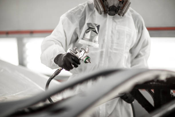 technicien de peinture appliquant la peinture à une partie de voiture avec un pistolet de pulvérisation dans un magasin de carrosserie de voiture - carrosserie photos et images de collection