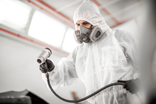 Car painter using a pneumatic air dryer to quickly dry out a coat of paint on a car part Car painting technician using a pneumatic air dryer to dry a paint on a car section in a painting chamber. protective mask workwear stock pictures, royalty-free photos & images