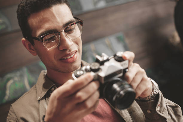 istock Handsome young man looking at retro camera and smiling 1135935072