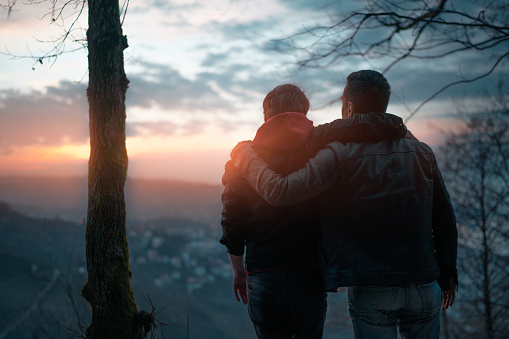 Rear view of friends watching the sunset over the cliff with city view