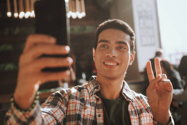 istock Handsome young man making selfie and showing victory gesture 1135936433