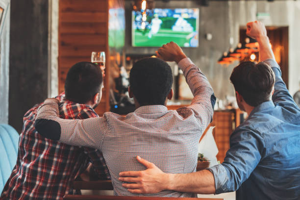 drei männer beim fußballspielen im fernsehen in bar - fußball wettbewerb stock-fotos und bilder