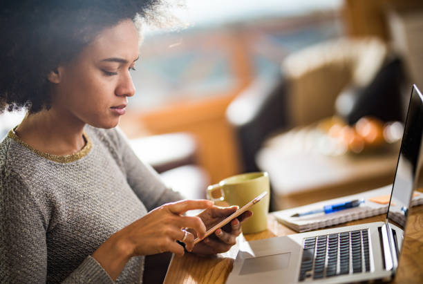 istock Young African American woman using cell phone while working at home. 1135938661
