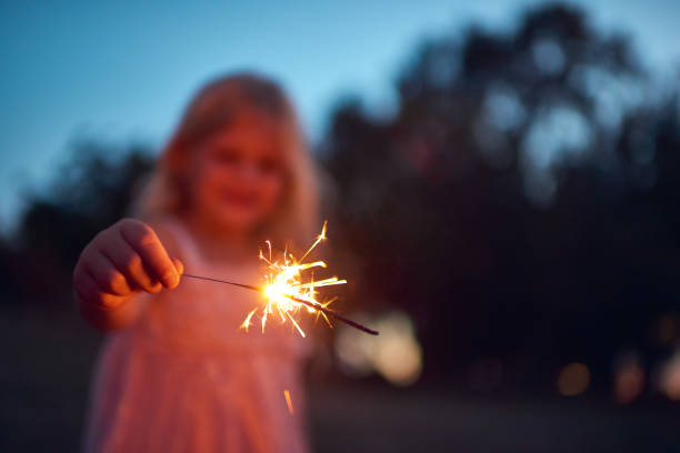She's lighting up the night Shot of an unrecognizable little girl playing with a sparkler at night time outside in nature dark pink dress stock pictures, royalty-free photos & images