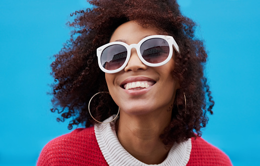 Cropped shot of a young woman wearing sunglasses against a blue background