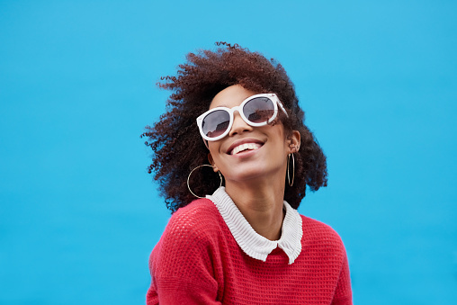 Cropped shot of a young woman wearing sunglasses against a blue background