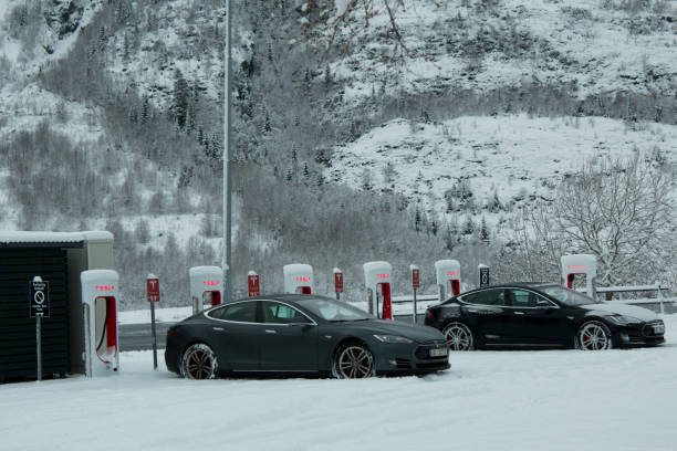 Tesla cars charging in electric station In the fjord of Mosjøen, in the city of Mosjøen, Tesla has a charging station for electric cars, very popular in Norway. The view with the snow and the fjord in the back is very interesting. Here we can see two Tesla cars charging energy fuel and power generation city urban scene stock pictures, royalty-free photos & images