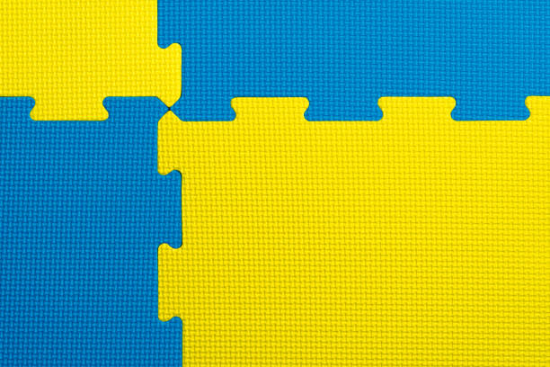 Interlocking blue and yellow EVA foam flooring tiles inside a gym, nursery, play room or school classroom Interlocking blue and yellow EVA foam flooring tiles inside a gym, nursery, play room or school classroom. Potential use as a colourful background with copy space. beach mat stock pictures, royalty-free photos & images