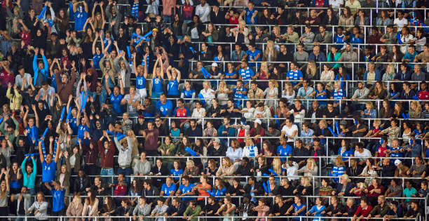 Group of spectators cheering in stadium Blurred motion of group of fans cheering while watching match in stadium. doing the wave stock pictures, royalty-free photos & images