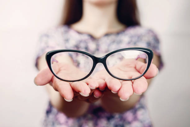 istock glasses on female hand on grey background 1135943946
