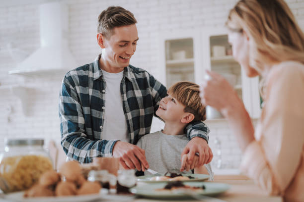 istock Positive man smiling to his son while cutting food with him 1135944291
