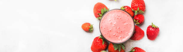 Strawberry smoothie in bottles on white table, top view, copy space, top view, banner