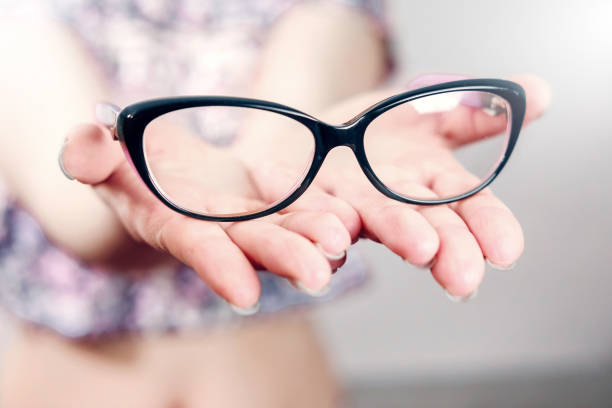 istock glasses on female hand on grey background 1135945057