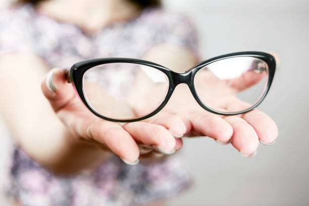 istock glasses on female hand on grey background 1135945790