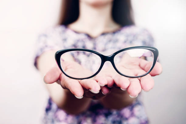istock glasses on female hand on grey background 1135945908