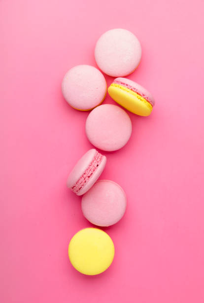 istock Pink yellow macaroons on soft pink background table, place for text, minimalism style, top view 1135946078