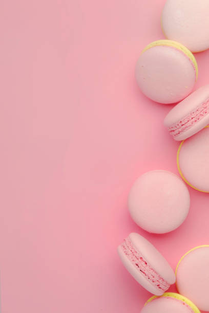 istock Pink yellow macaroons on soft pink background table, place for text, minimalism style, top view 1135946087
