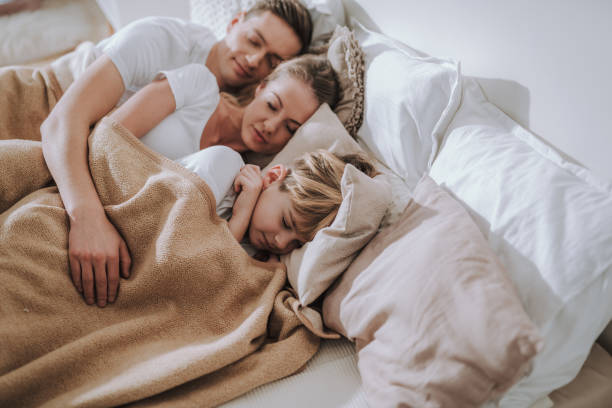 istock Beautiful family sleeping in one bed and looking peaceful 1135946253