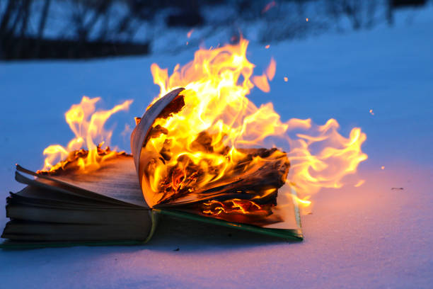 istock burning book in  snow. pages with the text in  open book burn with  bright flame. 1135948437