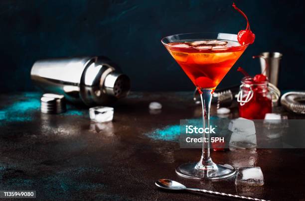 Classic Alcoholic Cocktail Manhattan With Bourbon Red Vermouth Bitter Ice And Cocktail Cherry In Glass Gray Bar Counter Background Place For Text Selective Focus Stock Photo - Download Image Now