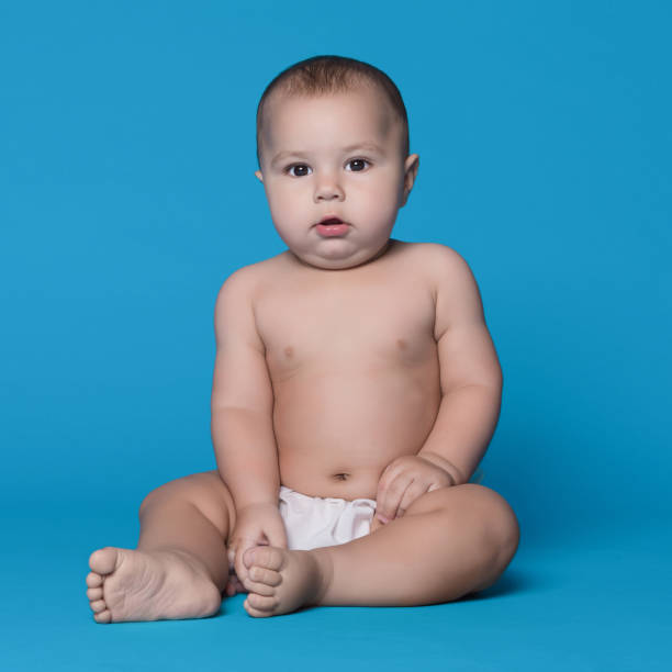 istock Cute baby boy looking at camera on blue background 1135950325