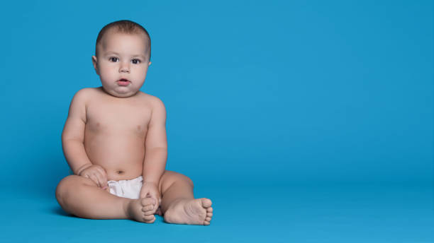 istock Cute baby boy looking at camera on blue background 1135950327