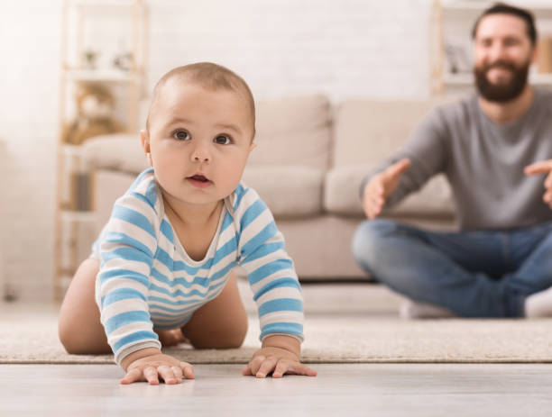 istock Adorable baby boy crawling on floor with dad 1135950334