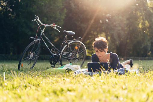 Young adult woman reading an ebook at a public park