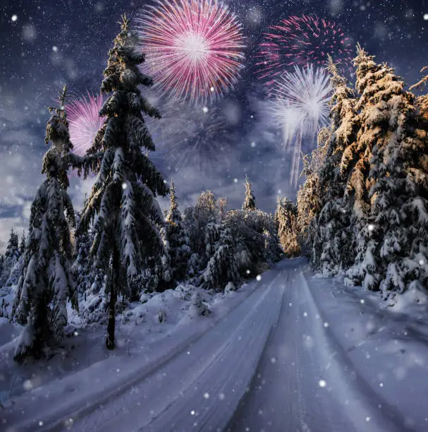 Photo of starry sky in winter snowy night. fantastic milky way in the New Year's Eve. Winter road in the mountains. fireworks and holiday lights on the background. Photo greeting card
