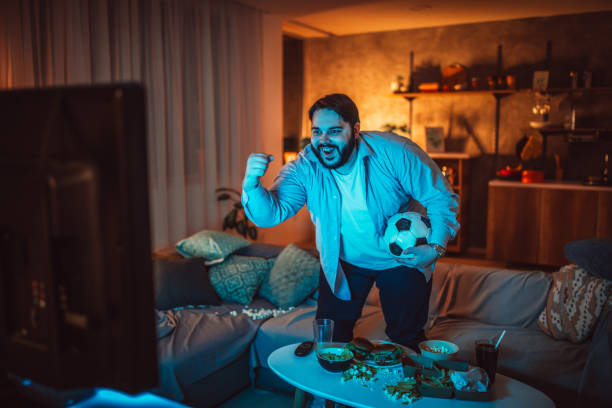 Overweight guy watching a soccer match at home