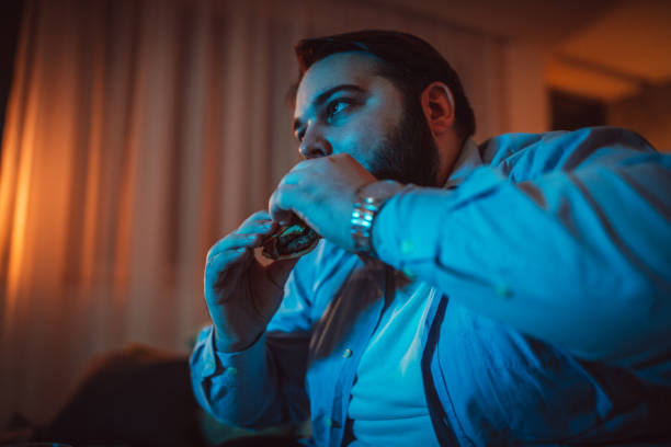 istock Overweight man eating burger at home 1135954258