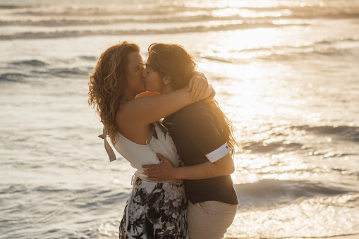 Young adult couple kissing together on the beach