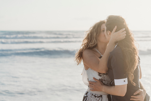 Young adult couple kissing together on the beach