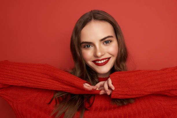istock Happy young woman pulling the sweater on red background 1135955043