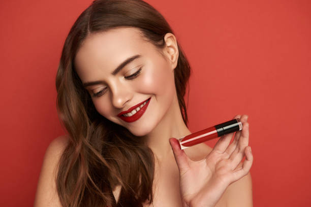 istock Smiling lady showing bright lipstick on red background 1135955069