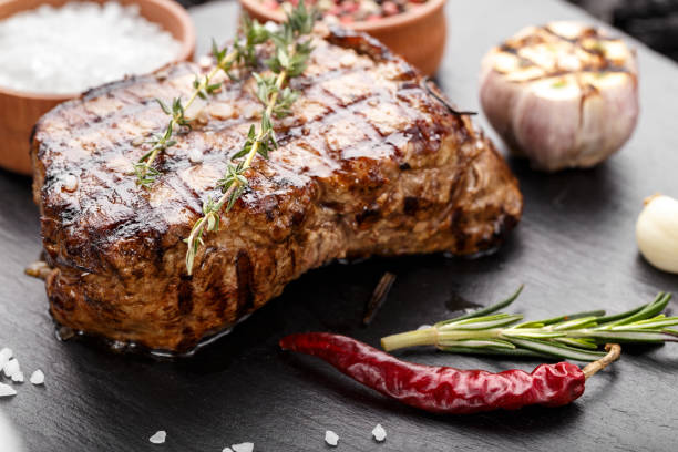 istock grilled beef steak with spices on a black slate board. 1135955673