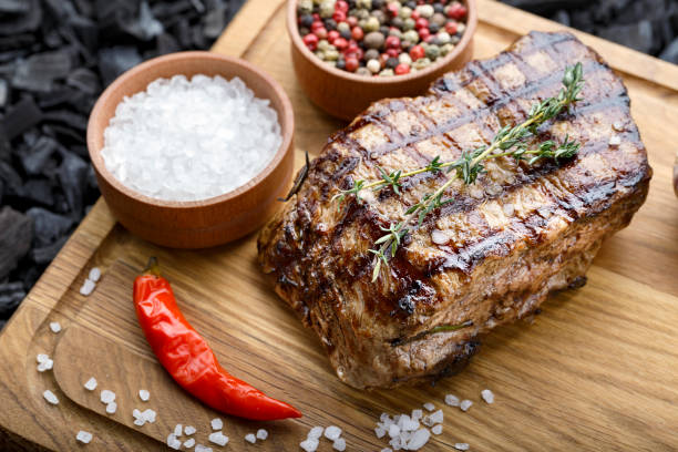 istock grilled beef steak with spices on a wooden cutting board. 1135955694