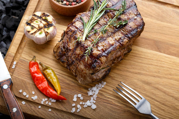 steak de boeuf grillé avec des épices sur une planche à découper en bois. - close up roasted meal pepper photos et images de collection