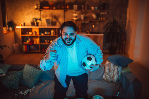 istock Chubby guy watching a soccer match at home 1135955874